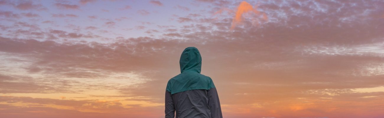 young-woman-standing-on-a-mountain-looking-over-the-clouds